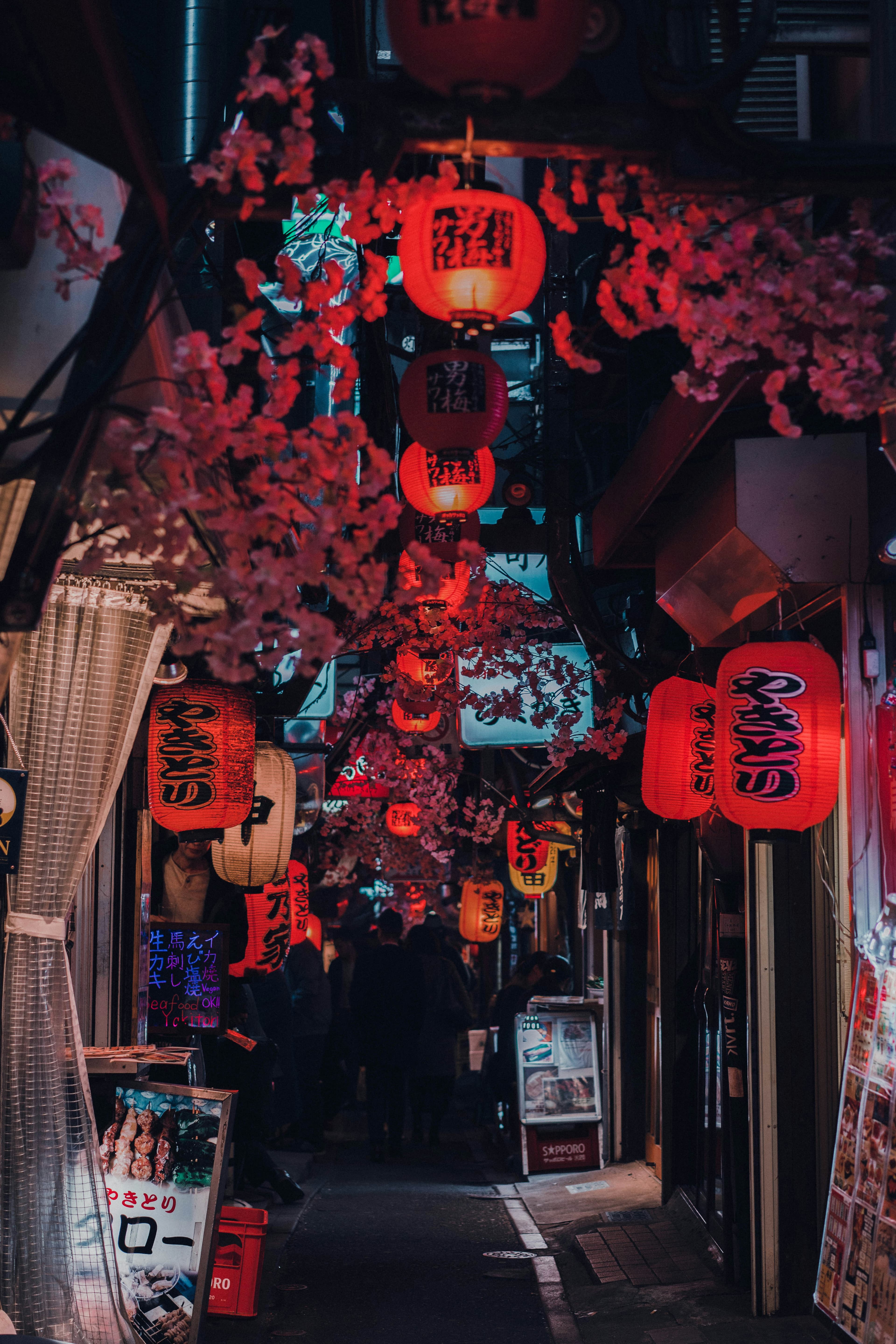 A narrow ramen alley glowing under a red paper lantern, a lone diner hunched at a counter.