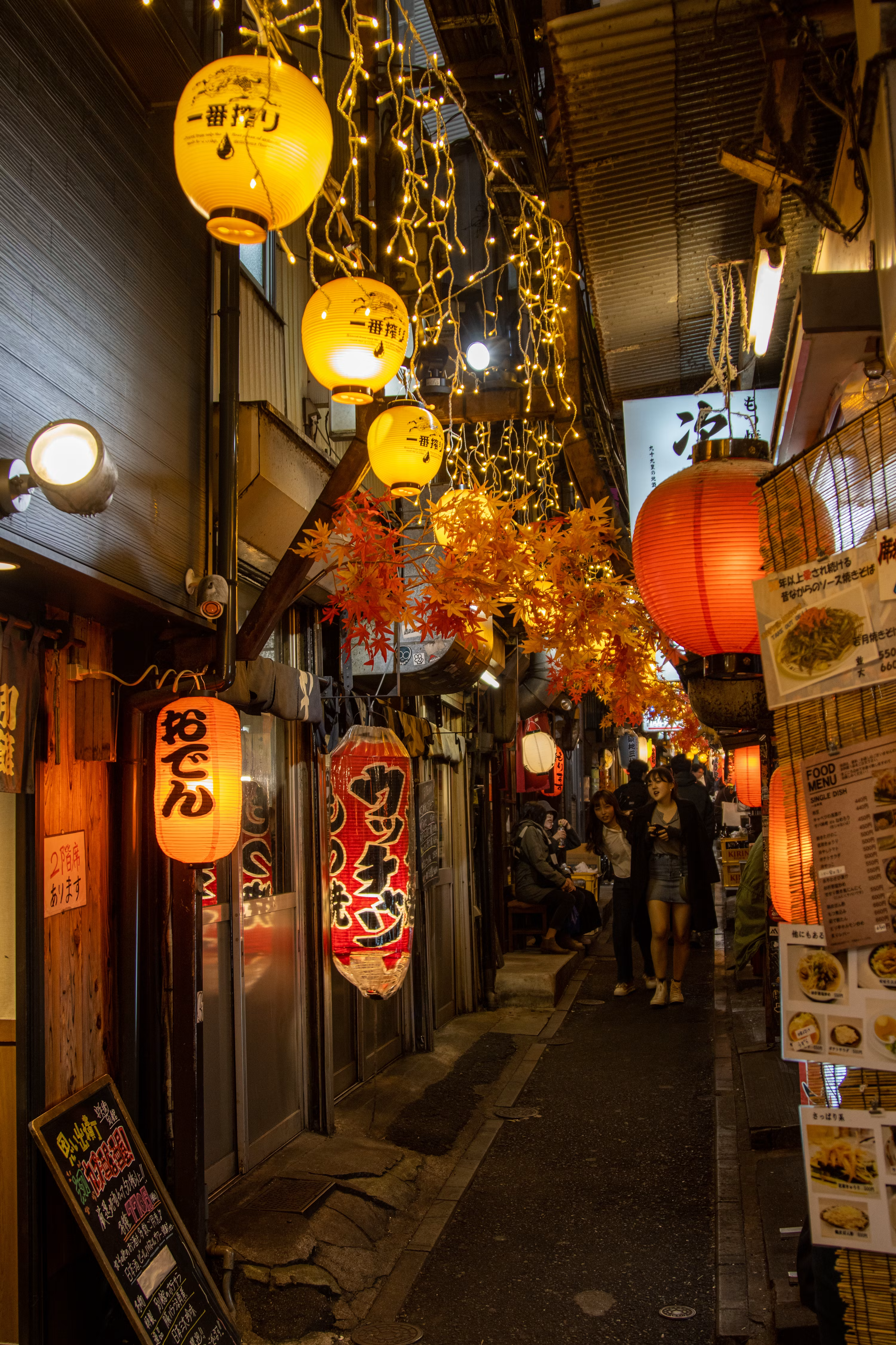 A rain-glossed lantern-lit street at dusk, a pagoda silhouetted against the deep blue evening.